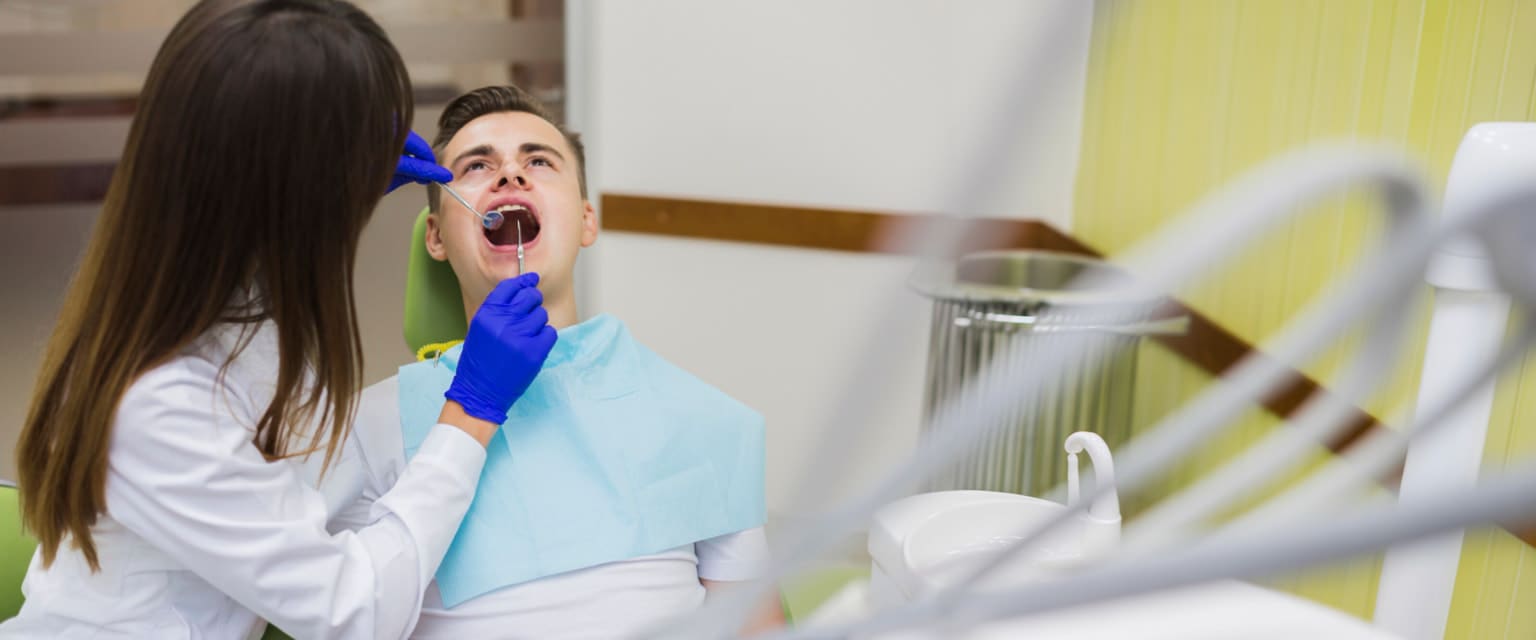 At Stellar Orthodontics in San Marcos, CA, a dentist examines a male patient’s metal braces with dental tools visible nearby.
