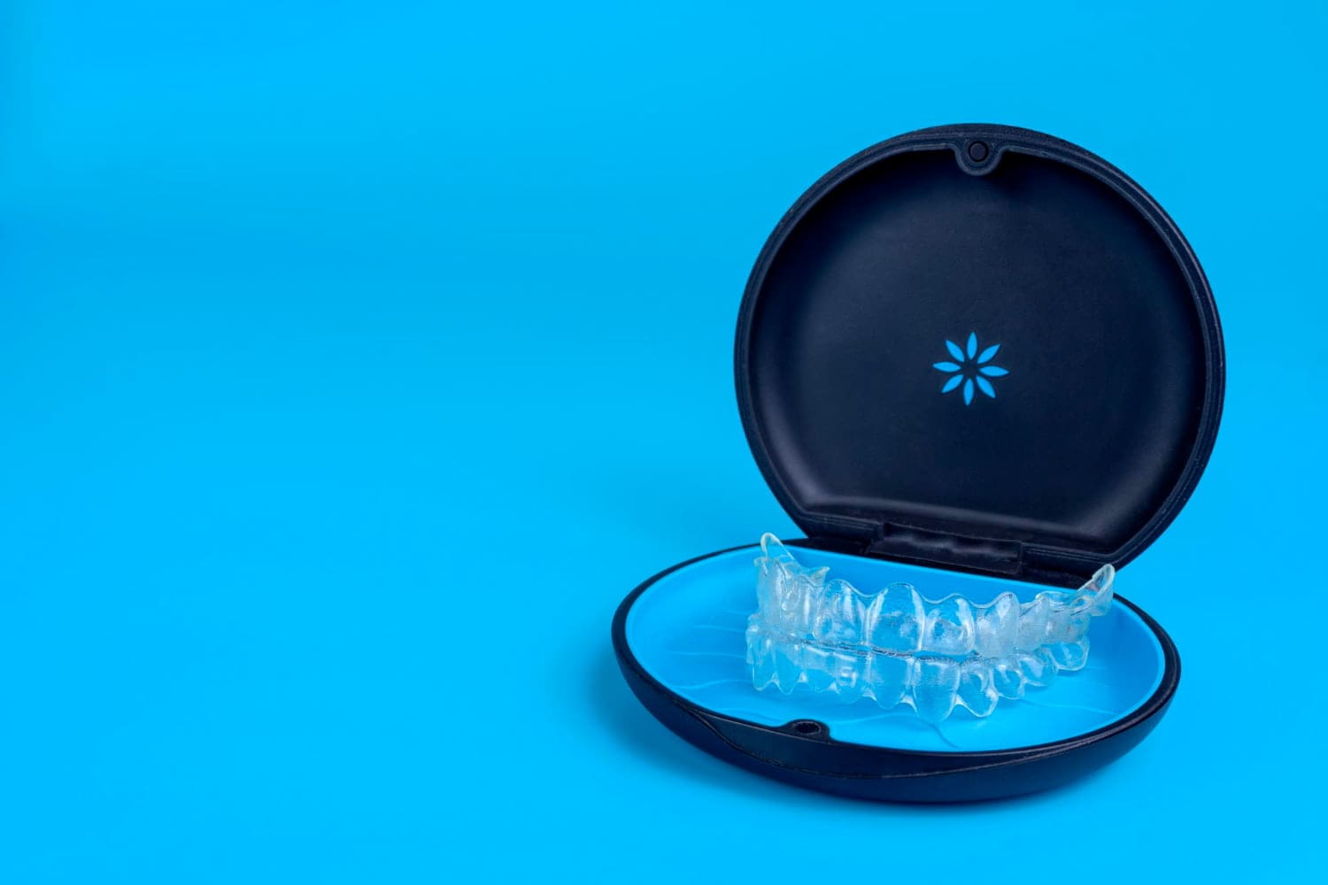 An invisalign in a black round case, displayed on blue, representing affordable Invisalign cost at Stellar Orthodontics in San Marcos, CA.