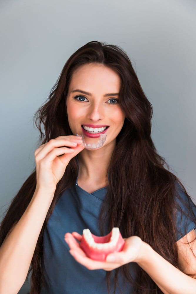 Smiling at the camera, a woman in scrubs at Stellar Orthodontics in San Marcos, CA, represents an affordable Invisalign cost.